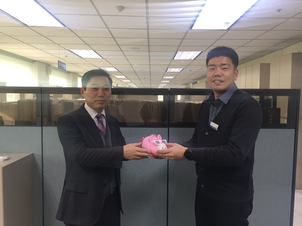 김선용 재정과장이 건강과 행운을 기원하는 마음을 담아 복(福)돼지 저금통을 돼지띠 직원에게 선물하고 있다.